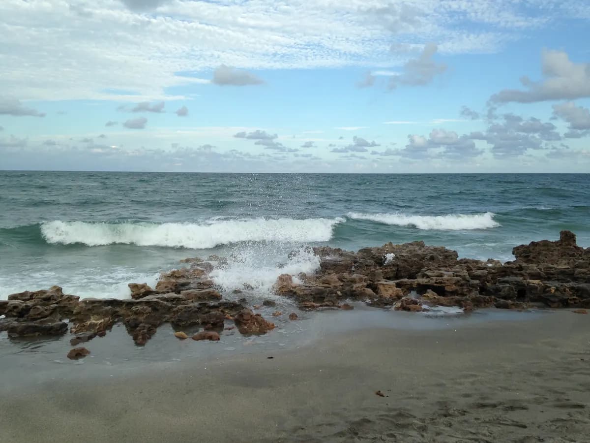 Waves breaking over rocks at Coral Cove Park beach in Tequesta, Florida